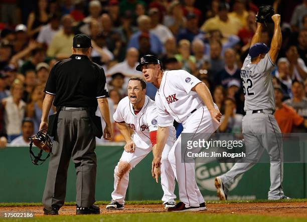Daniel Nava and Brian Butterfield of the Boston Red Sox plead their case after umpire Jerry Meals called Nava out at the plate against the Tampa Bay...