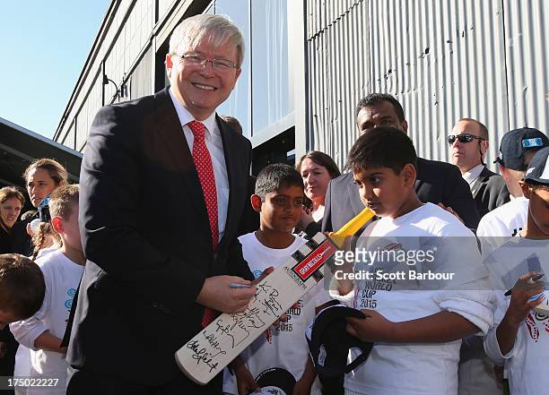 Australian Prime Minister Kevin Rudd signs a cricket bat as he poses with children during the Official Launch of the ICC Cricket World Cup 2015 on...