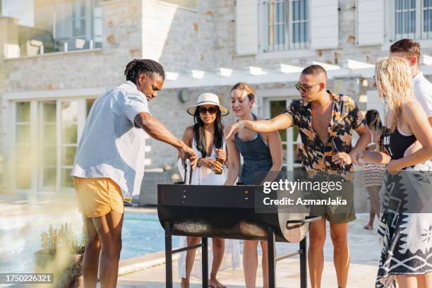 a multiracial group of close friends barbecuing together poolside - party host stock pictures, royalty-free photos & images