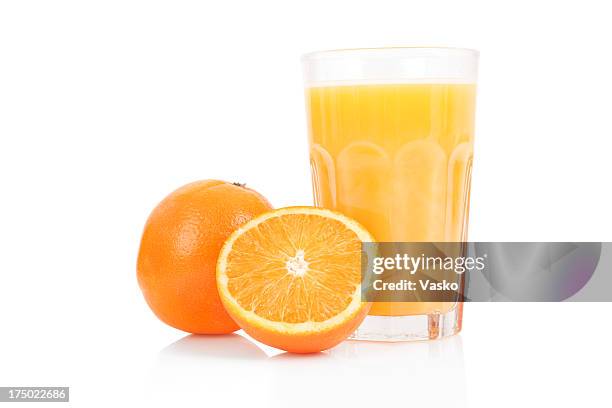 fresh orange juice in glass cup next to a sliced orange - vruchtensap stockfoto's en -beelden