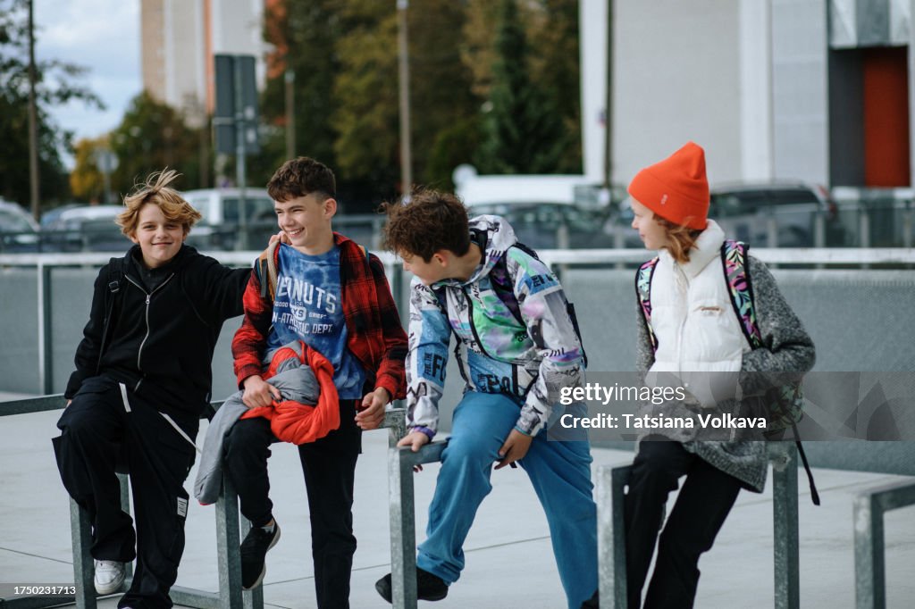 Small group of school friends takes moment to relax perched on rectangular bicycle racks
