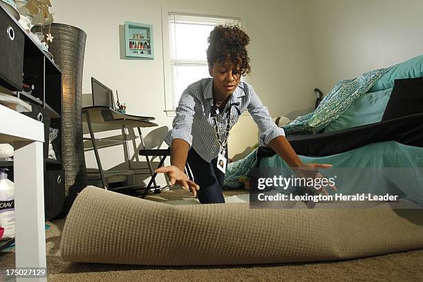 Anyssa Roberts rolls out an Xhilaration Shag Accent Rug from Target, $44, as she shows some interior design techniques, July 22 in Lexington,...