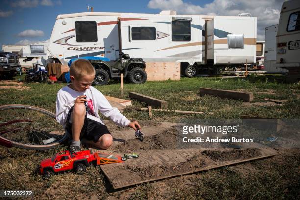 Boy plays with toy motorcycles in a trailer park on July 29, 2013 in Watford City, North Dakota. The trailer park is intended for oil workers...