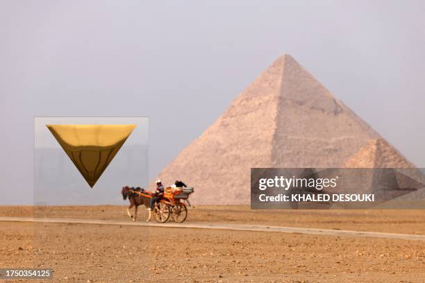 Tourists ride in a horse-drawn carriage near the art installation "Temple" by French artist Stephan Breuer and the Pyramid of Menkaure or Menkheres...