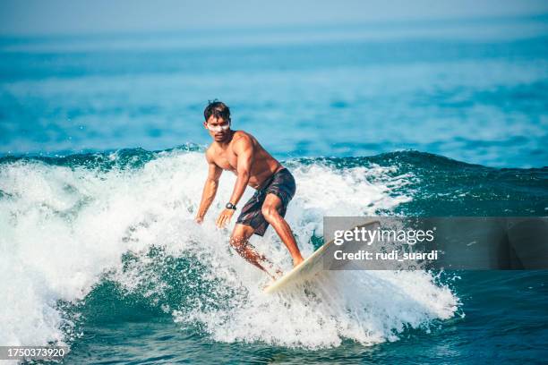 surfer riding wave at sunrise - polynesische etniciteit stockfoto's en -beelden