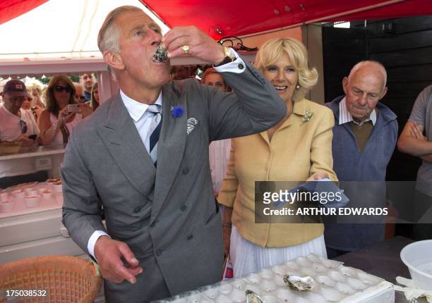 Britain's Prince Charles, the Prince of Wales samples an oyster as Camilla, the Duchess of Cornwall looks on during a visit to the Whitstable Oyster...