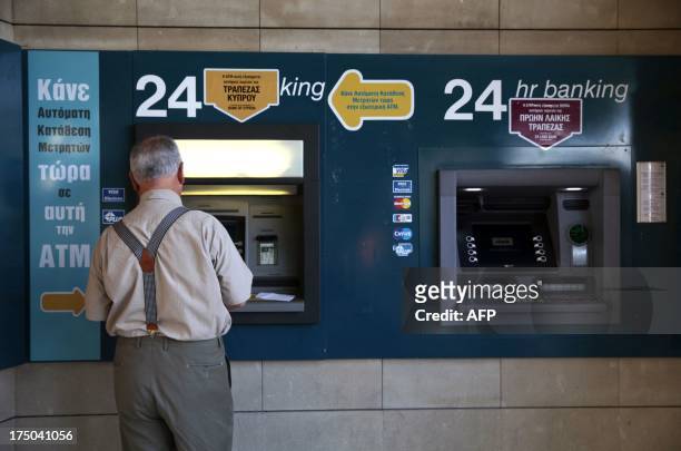Man withdraws money at an ATM at a Bank of Cyprus branch in the capital, Nicosia, on July 30, 2013. Cyprus's central bank agreed a 47.5 percent...