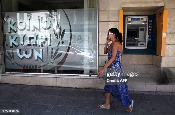 Woman walks past an ATM at a Bank of Cyprus branch in the capital, Nicosia, on July 30, 2013. Cyprus's central bank agreed a 47.5 percent haircut...