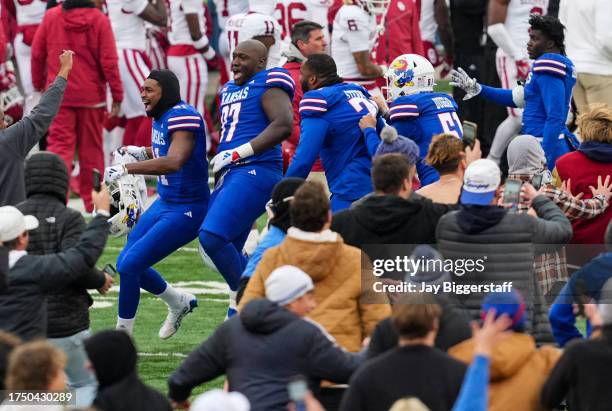 Kansas Jayhawks players celebrate with fans on the field after defeating the Oklahoma Sooners at David Booth Kansas Memorial Stadium on October 28,...