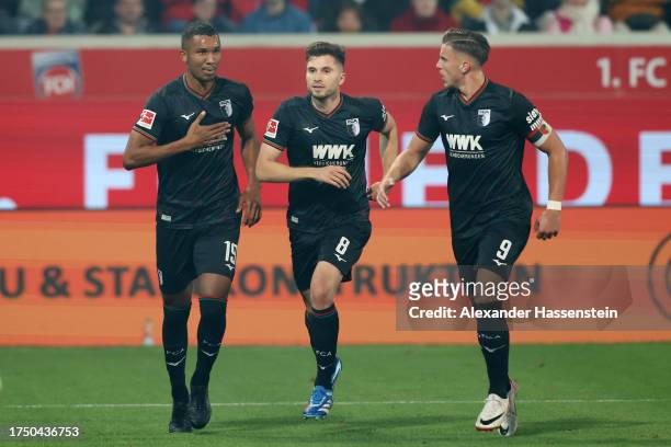 Felix Uduokhai of FC Augsburg celebrates with Elvis Rexhbecaj and Ermedin Demirovic of FC Augsburg after scoring the team's fourth goal during the...