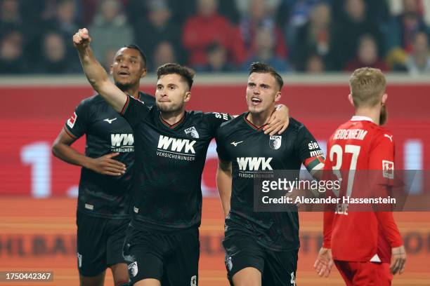 Elvis Rexhbecaj and Ermedin Demirovic of FC Augsburg celebrate as Felix Uduokhai of FC Augsburg scores the team's fourth goal during the Bundesliga...