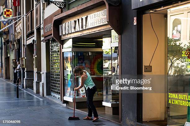 Worker sweeps the pavement in front of a store in the Catalan town of Manresa, Spain, on Tuesday, July 30, 2013. Spain's recession eased in the...