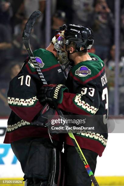 Travis Dermott of the Arizona Coyotes and Karel Vejmelka celebrate after a 2-1 victory over the Anaheim Ducks at Mullett Arena on October 21, 2023 in...