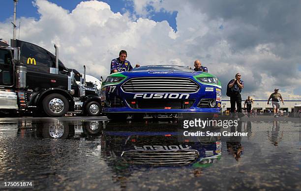 Crew members push the Fifth Third Bank Ford of Ricky Stenhouse Jr. Through the garage prior to the NASCAR Sprint Cup Series Quaker State 400 at...