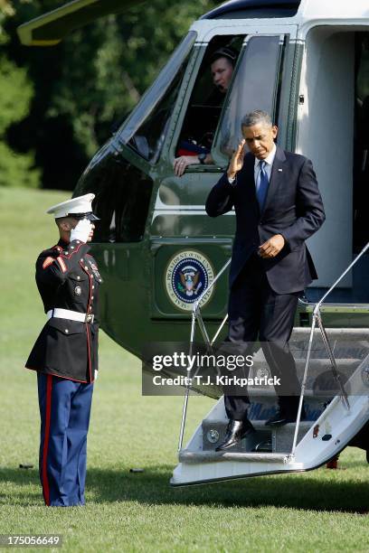 President Barack Obama salutes a Marine guard while departing from Marine One as he returns to the White House, after speaking at the Amazon...