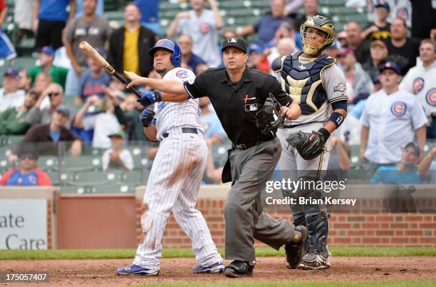 Welington Castillo of the Chicago Cubs , home plate umpire Jim Reynolds and catcher Martin Maldonado of the Milwaukee Brewers watch to see if a long...