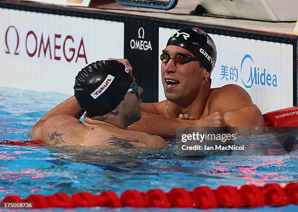 Matt Greave of USA is congratulated by his team mate David Plummer on his victory in the Men's 100m Backstroke Final at the Palau Sant Jordi on day...