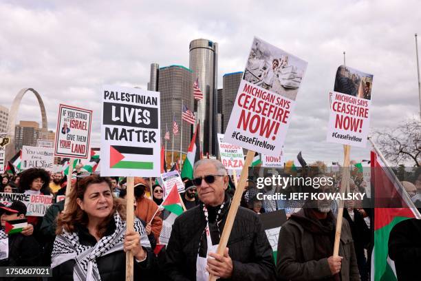 People hold signs as they gather in Hart Plaza in downtown Detroit, Michigan to call for a ceasefire and voice their support for the Palestinian...