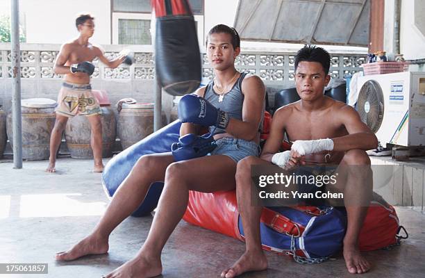 Transvestite boxer Parinya Kiatbusaba takes a break with one of his pals at the Paiyanan boxing camp in Cholburi province. Parinya has since had a...