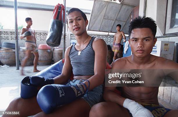 Transvestite boxer Parinya Kiatbusaba takes a break with one of his pals at the Paiyanan boxing camp in Cholburi province. Parinya has since had a...