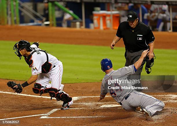 John Buck of the New York Mets slides into home plate during a game against the Miami Marlins at Marlins Park on July 30, 2013 in Miami, Florida.