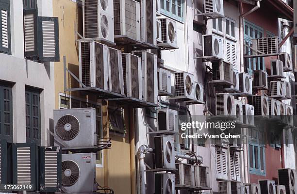 Mass of air conditioning units hang off the back side of a row of buildings..