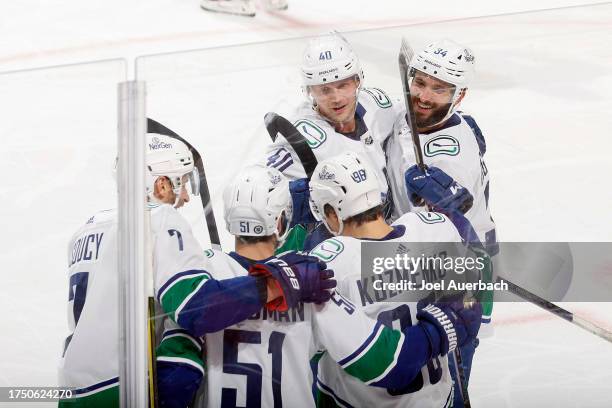 Teammates congratulate Andrei Kuzmenko of the Vancouver Canucks after he scored the game winning goal against the Florida Panthers during third...