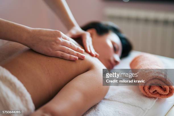 woman making massage in a beauty saloon. concept about spa, relaxation, body care and people. back massage. - massagebal stockfoto's en -beelden