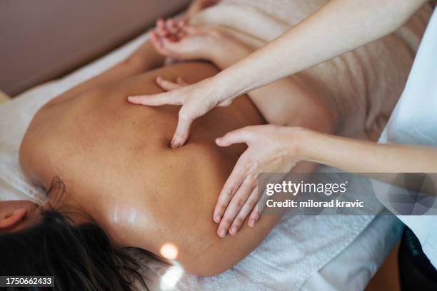 woman making massage in a beauty saloon. concept about spa, relaxation, body care and people. back massage. - massagebal stockfoto's en -beelden