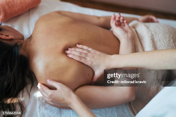 woman making massage in a beauty saloon. concept about spa, relaxation, body care and people. back massage. - massagebal stockfoto's en -beelden