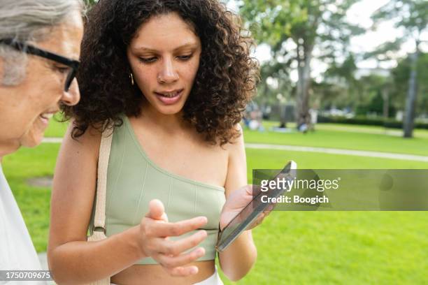 donna ispanica che mostra le foto alla nonna anziana sul telefono cellulare a winter park in florida - winter park florida foto e immagini stock