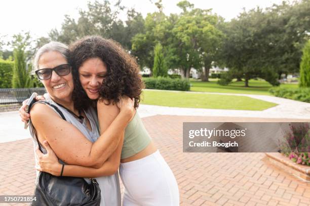 großmutter und erwachsene enkelin begrüßen sie mit einer umarmung in winter park, florida - puertoricanischer abstammung stock-fotos und bilder