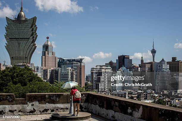 Woman views the Grand Lisboa Hotel and Casino from the Monte Fort on July 29, 2013 in Macau, Macau. Macau, the only place in China with legalized...