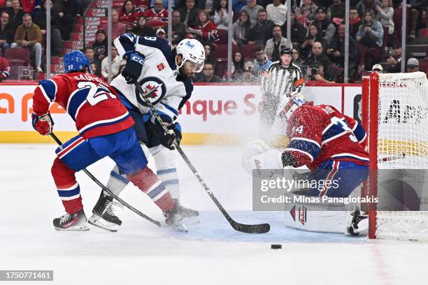 Alex Iafallo of the Winnipeg Jets skates the puck past Cole Caufield of the Montreal Canadiens towards goaltender Jake Allen during the first period...