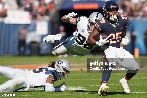 Running back Darrynton Evans of the Chicago Bears runs with the ball as defensive end Maxx Crosby of the Las Vegas Raiders dives for him during an...