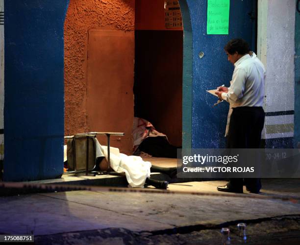 Forensic personnel work at the crime scene where two men and two women were killed inside a bar called "Mi Oficina" by gunmen in the Nezahualcoyotl...