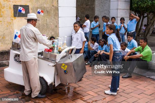 Vendor shaves a block of ice on a mobile cart to make snow cones for a waiting group of school children on the French Plaza in Casco Viejo, the...