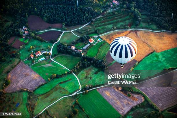 Hot air balloon flying La Fageda d' en Jorda and the volcanic area of Olot, the Natural Park of the Volcanic Zone of La Garrotxa and mountains on the...