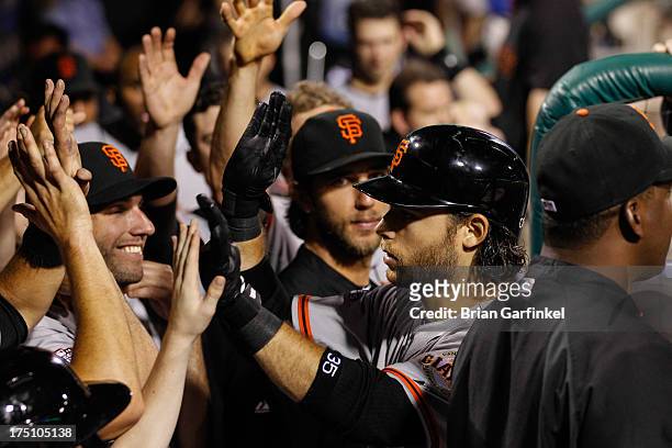 Brandon Crawford of the San Francisco Giants is congratulated by teammates in the dugout after hitting a solo home run in the seventh inning of the...