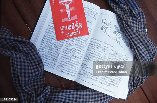 Copy of the bible translated into Khmer lies on the floor of a wooden hut, surrounded by a traditional Krama headscarf..