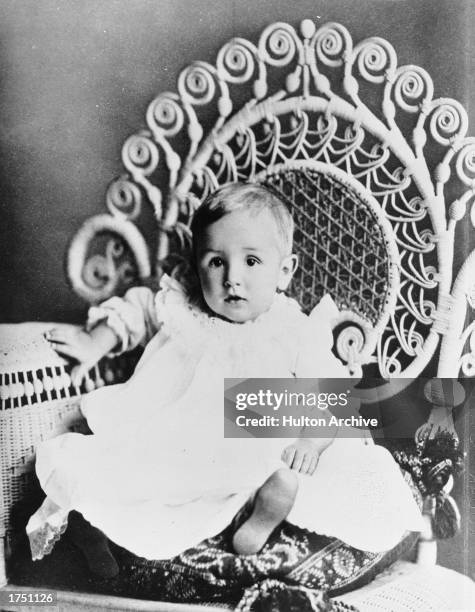 Studio portrait of future American film studio head Walt Disney as an infant, seated on an ornate chair, circa 1902.