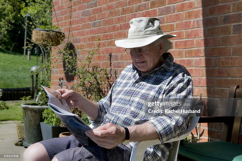 Senior man reading magazine in garden