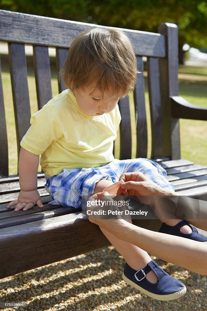 Mother putting sticking plaste on toddlers knee