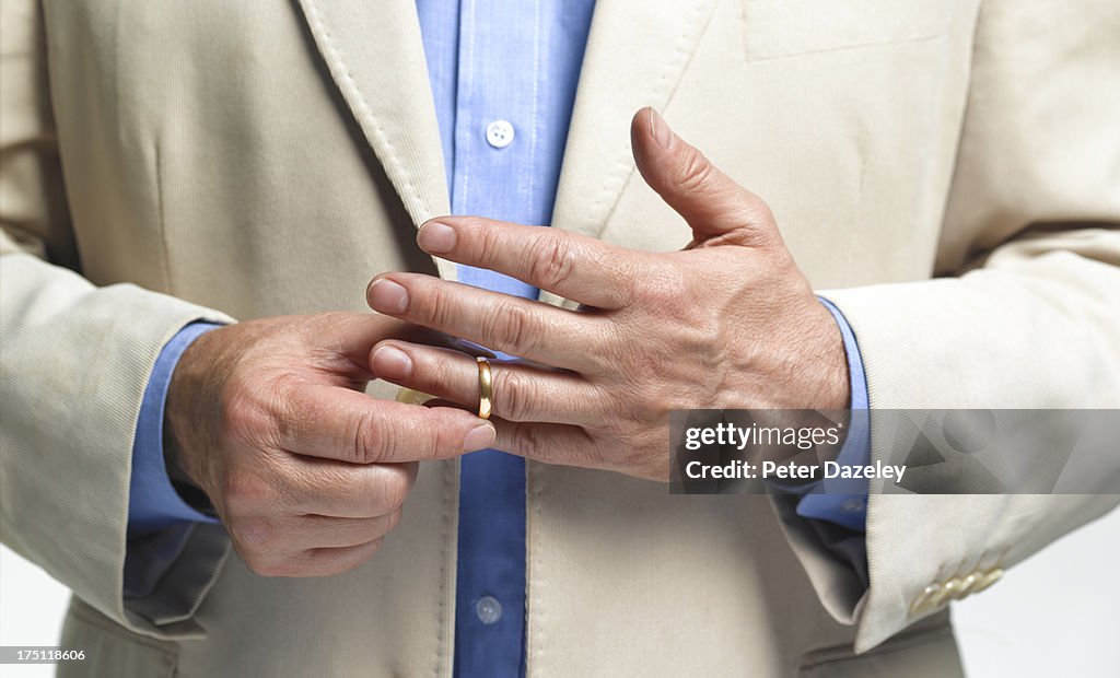 Divorced man taking off wedding ring