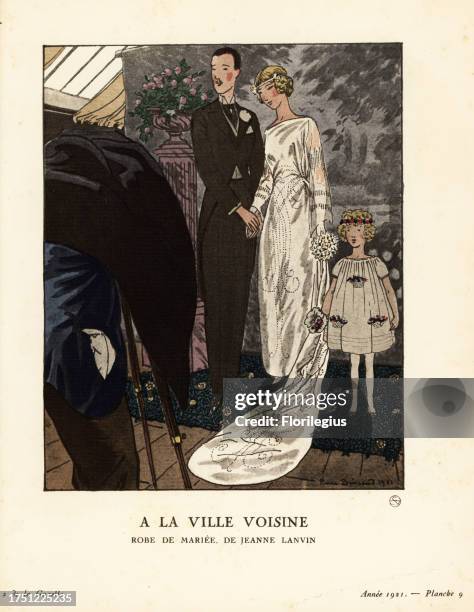 Woman in wedding dress in embroidered satin by Jeanne Lanvin, posing with groom and child in a photographer’s studio. A la ville Voisine. Robe de...