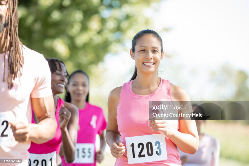 A woman in her prime joyfully participating in a charity race to support breast cancer awareness
