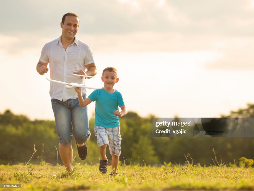 Father and son Having Fun With Toy Airplane Outdoors.