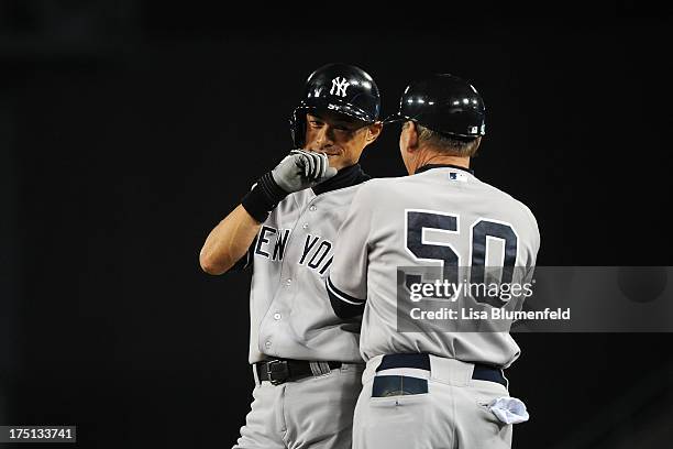 Ichiro Suzuki of the New York Yankees waits at first base with coach Mike Kelleher during the game against the Los Angeles Dodgers at Dodger Stadium...