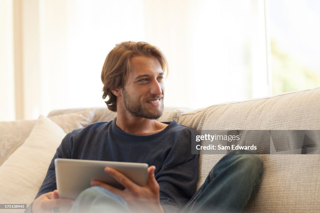 Man using tablet computer on sofa