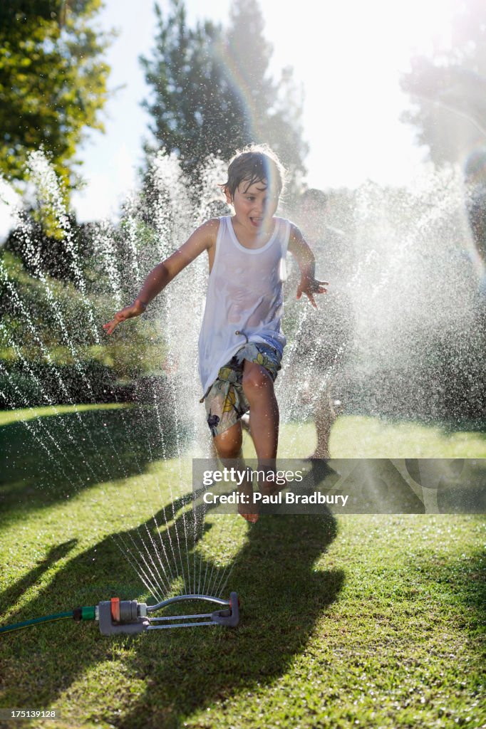 Boy playing in sprinkler in backyard